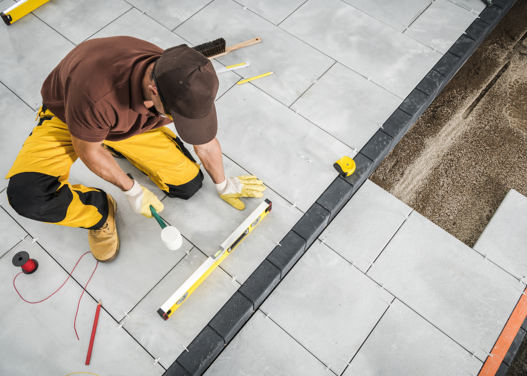 A worker installing a paver patio.