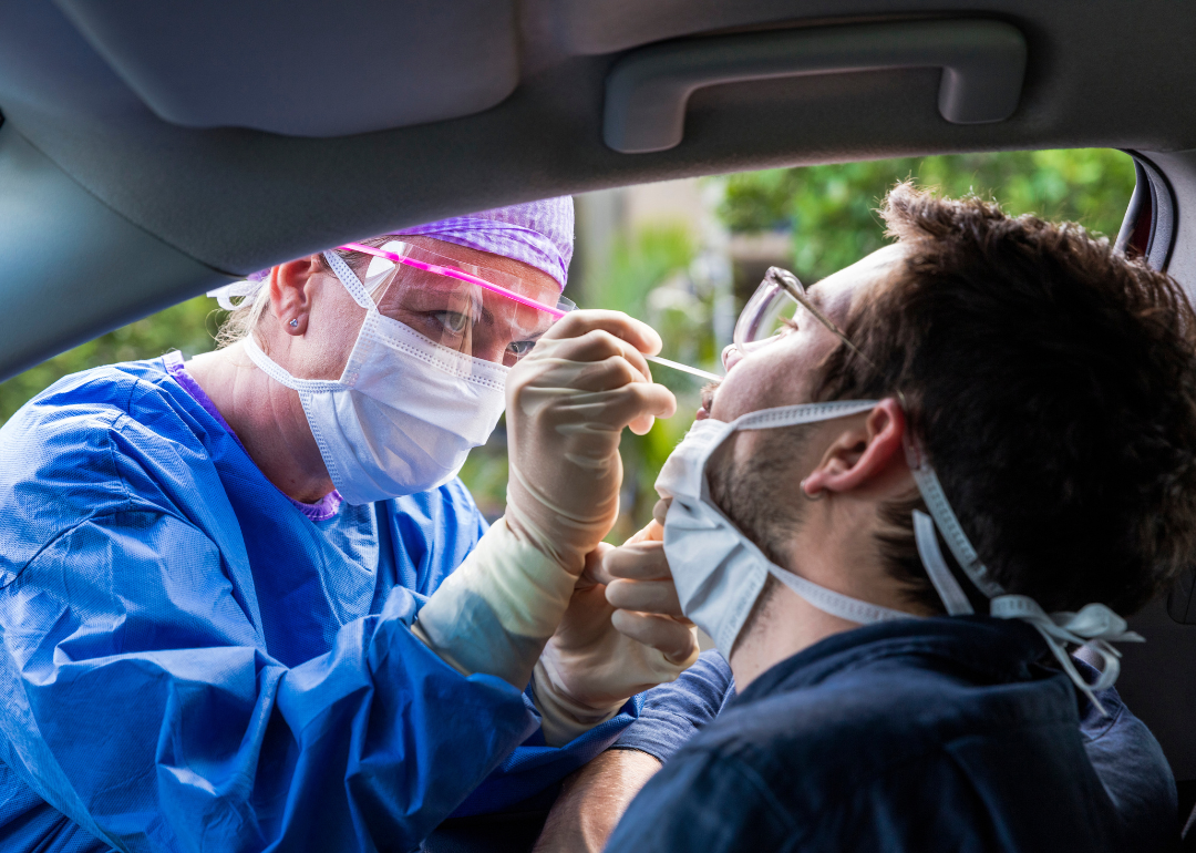 A doctor in a protective suit taking a nasal swab from a person to test for a possible coronavirus infection