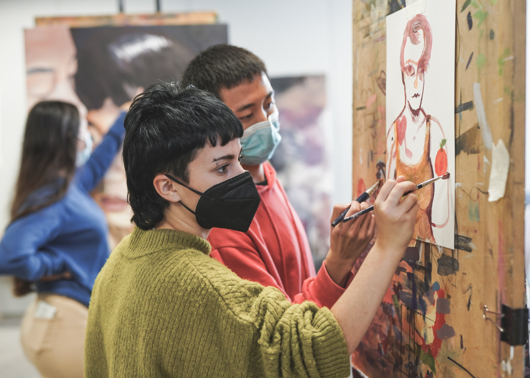Students painting together inside art room at school.