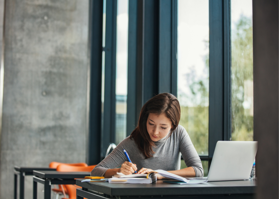 A student taking notes in a college classroom.