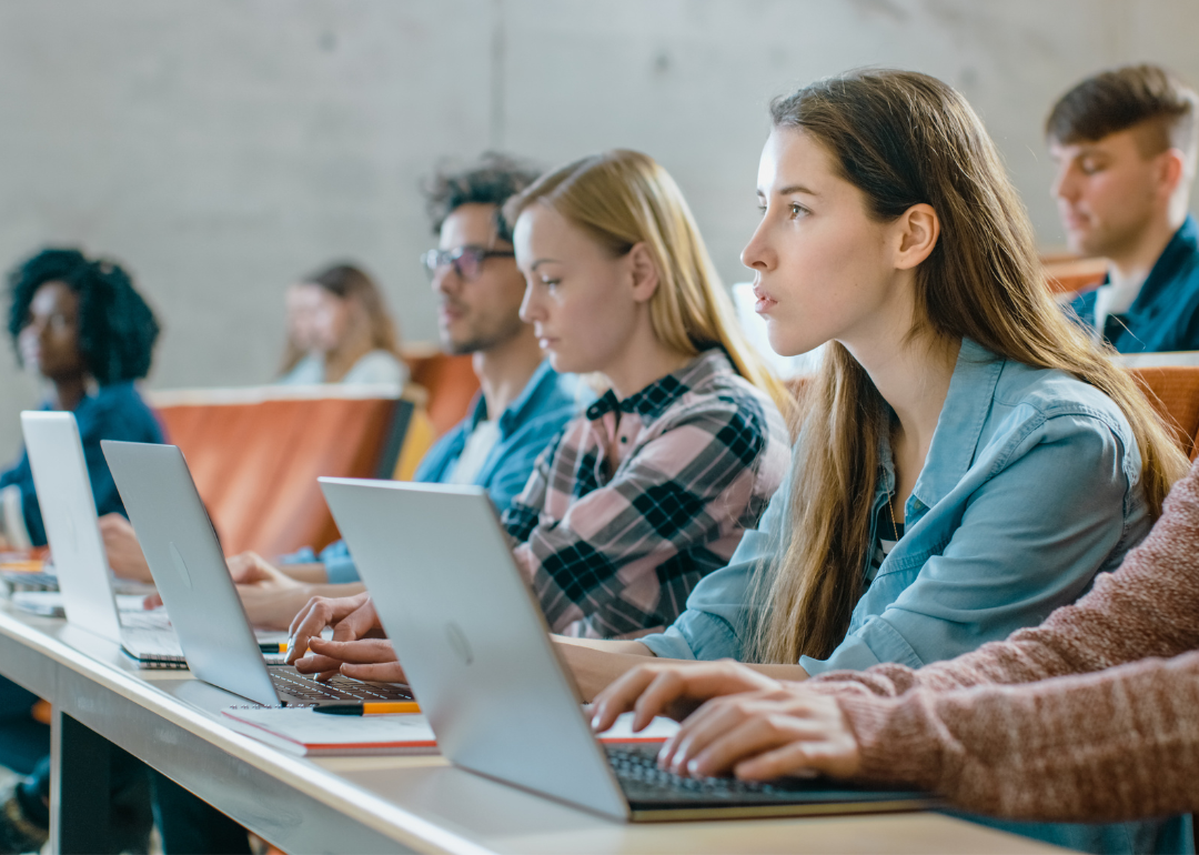 Students taking notes on their laptops during a college class.