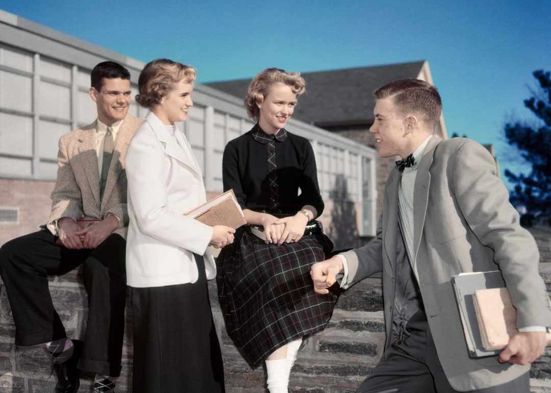 Four students talking outside a school building.