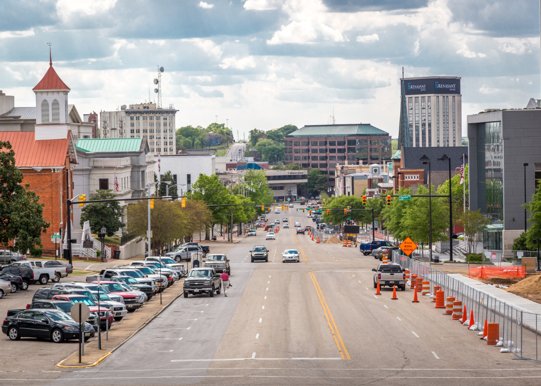 A street in downtown Montgomery with cars driving and parked on the road.