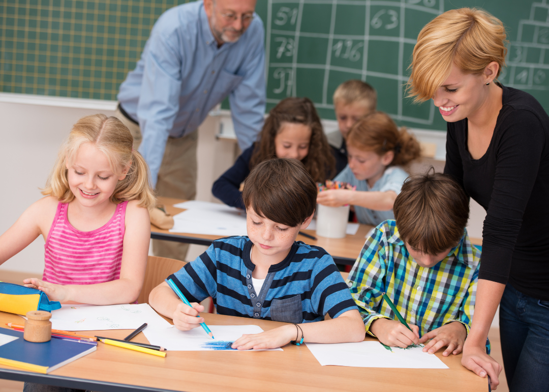 Two teachers helping students in a classroom