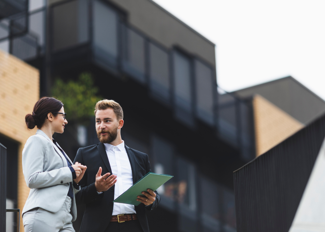 A real estate agent speaking with a client outside a home.