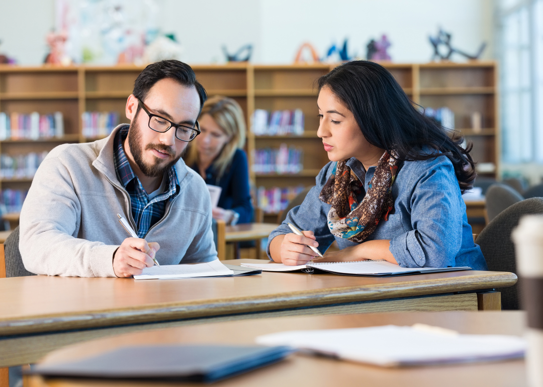 Two college students studying together in a classroom.