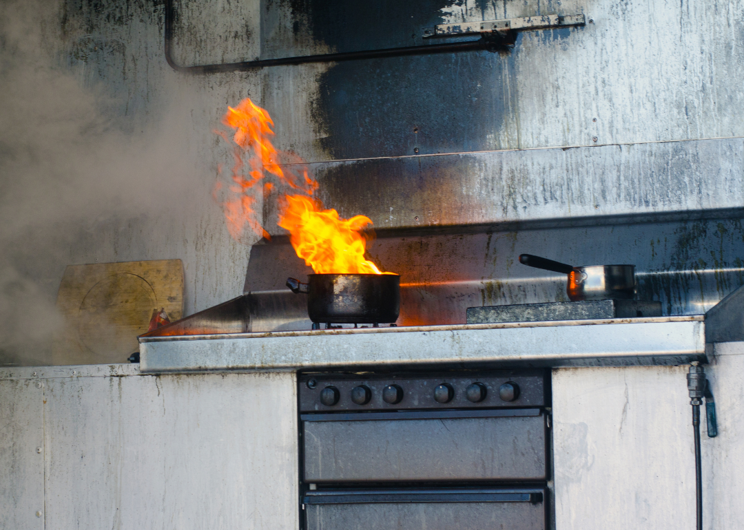 A pot on a stovetop left unattended on fire.