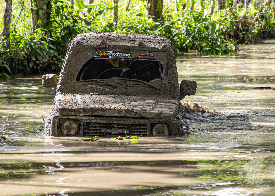A Suzuki Samurai going off road in a marsh/flooded area.
