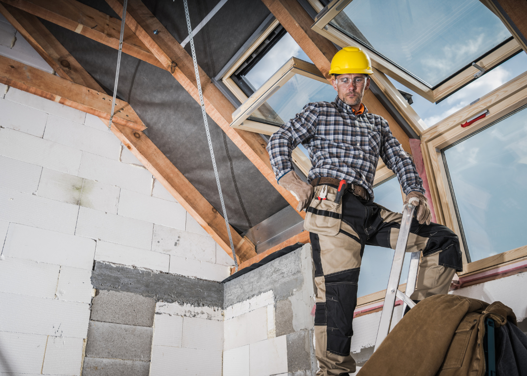 A construction worker installing a skylight in a house.