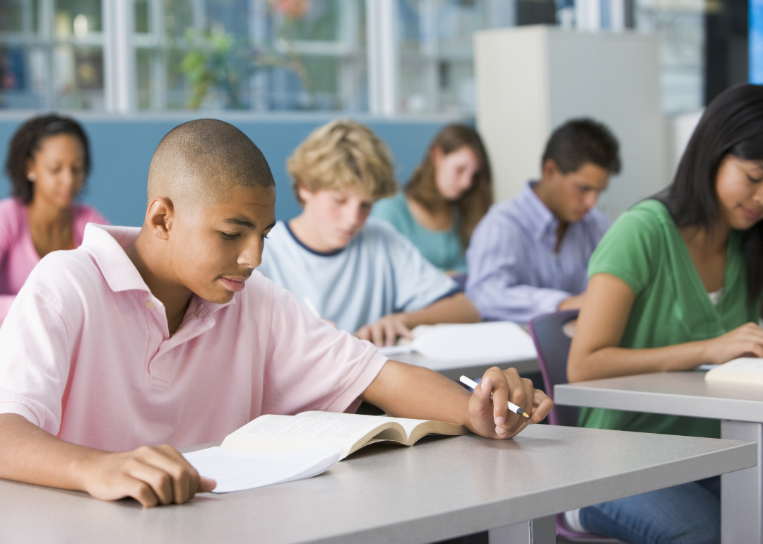 Students writing at their desks in class.