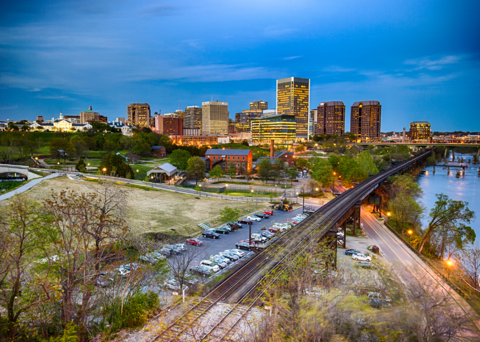 A city skyline at dusk with rail trucks and green grounds in the foreground.