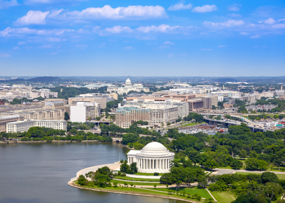Aerial view of town with white buildings, green spaces, and body of water.