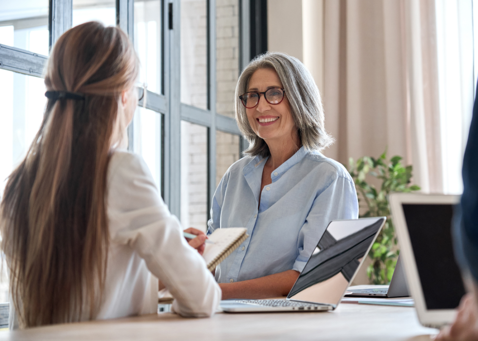 Two business women sitting across from each other at a desk.