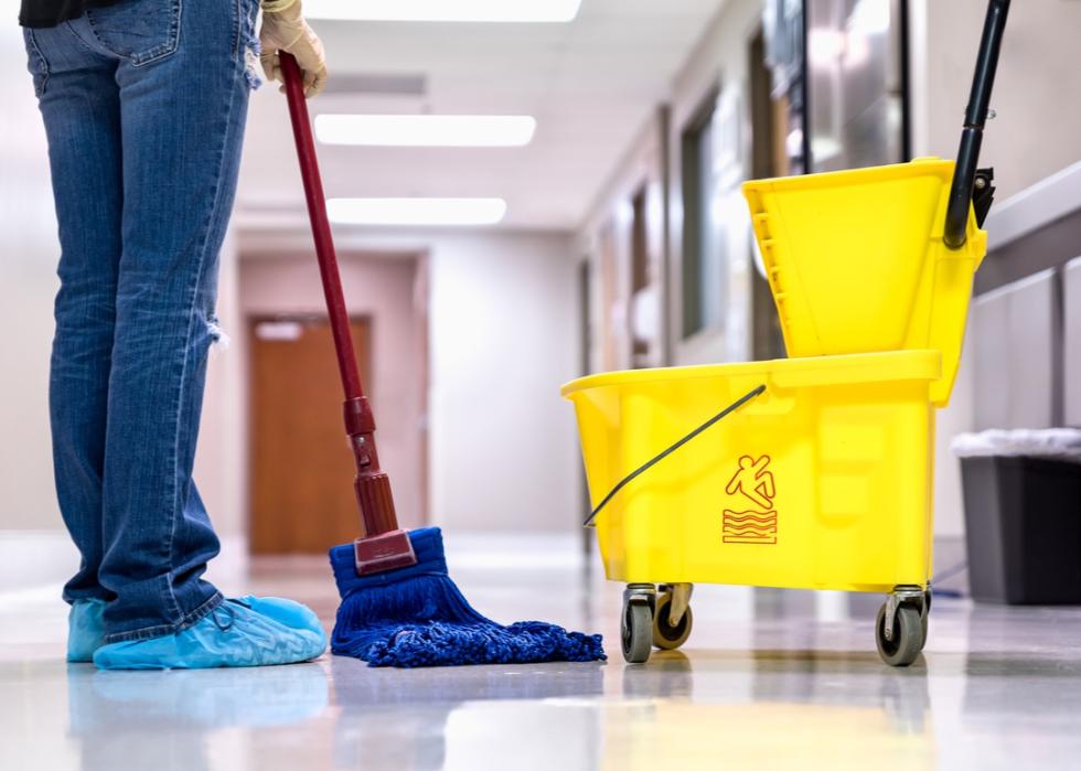 Janitor, shown from the waste down, getting ready to mop.