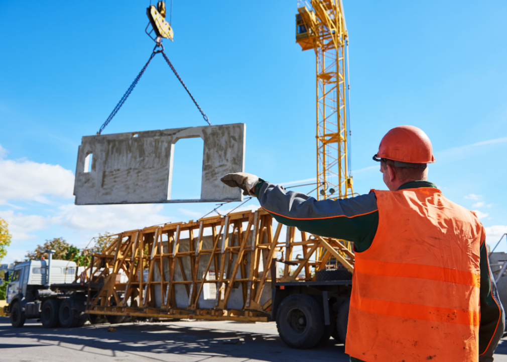 A worker guides a hoist and winch operator.