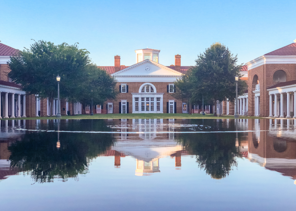 A reflective pond in front a white and red brick building.