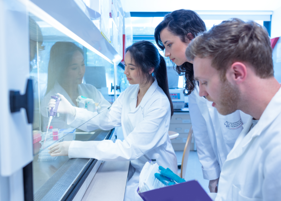 Three people wearing lab coats working in a lab.