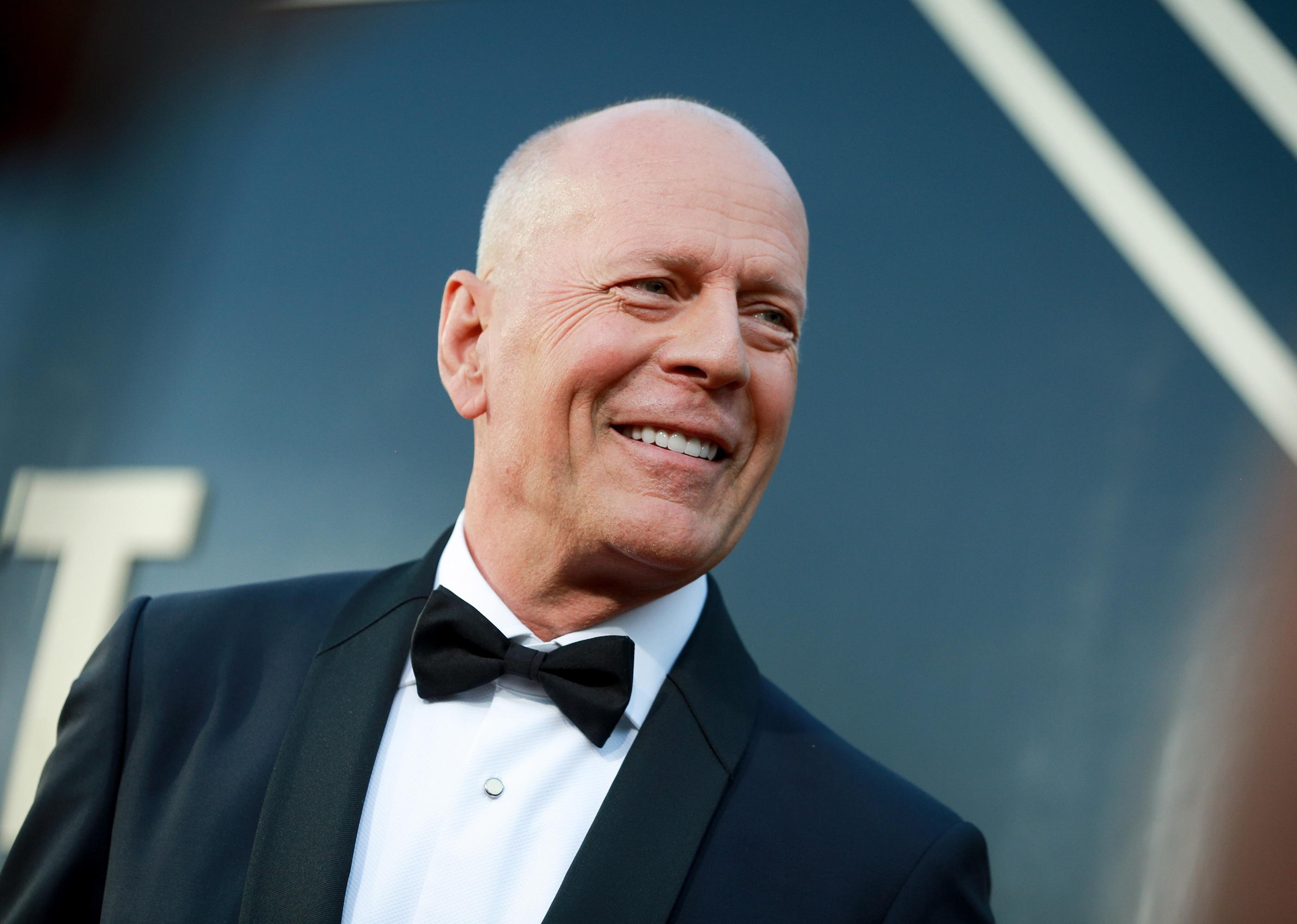 Bruce Willis in a black suit and bowtie.