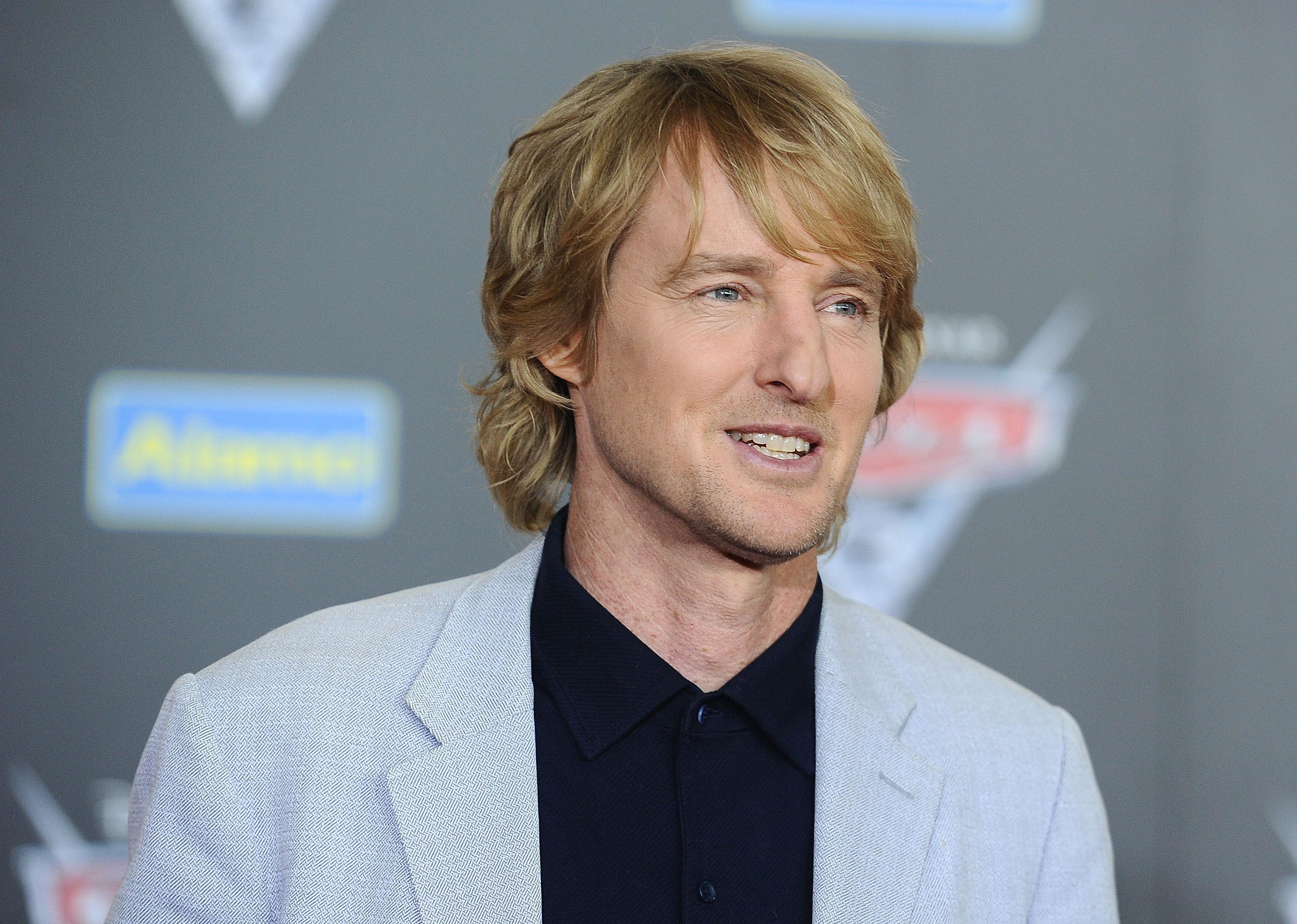 Owen Wilson in a grey blazer onstage.