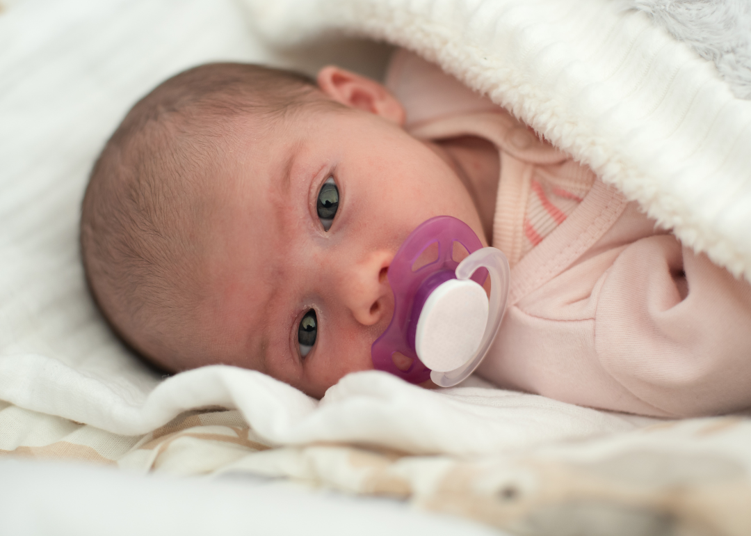 A baby in a blanket with a pacifier.