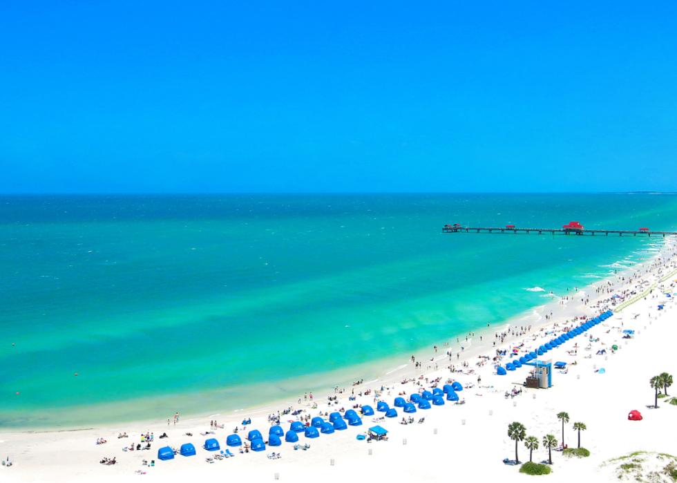 Aerial view of turquoise water and white sandy beach covered in beach umbrellas.
