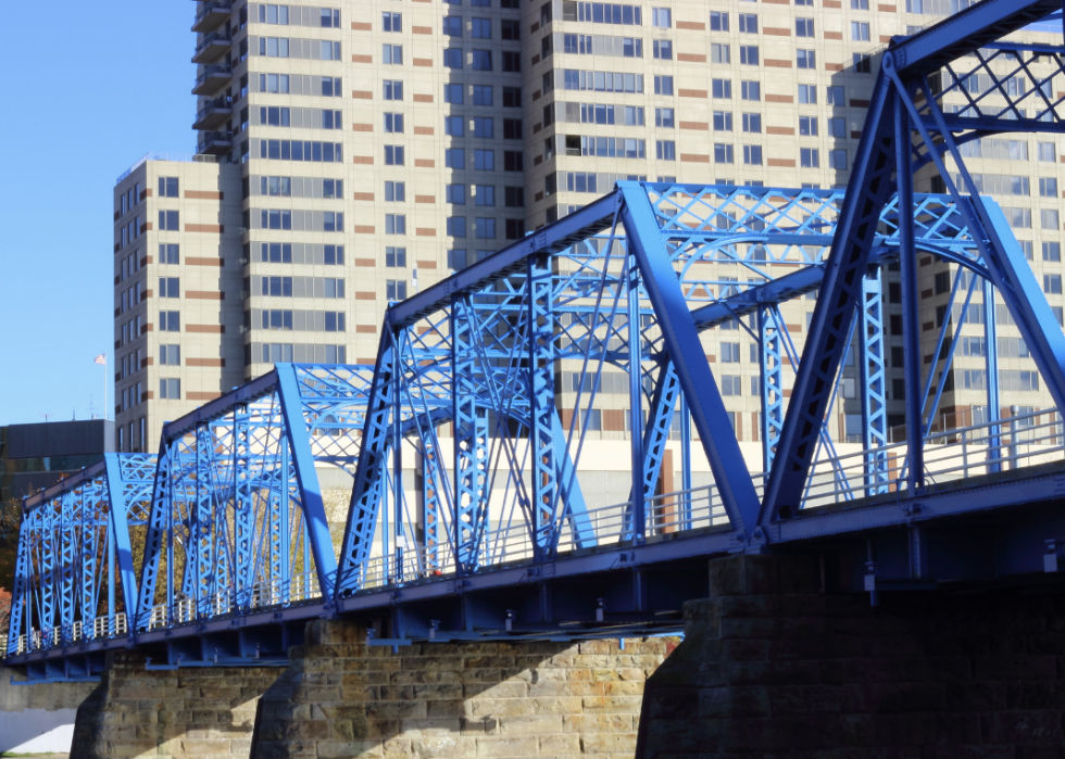 A blue bridge in front of tall buildings.
