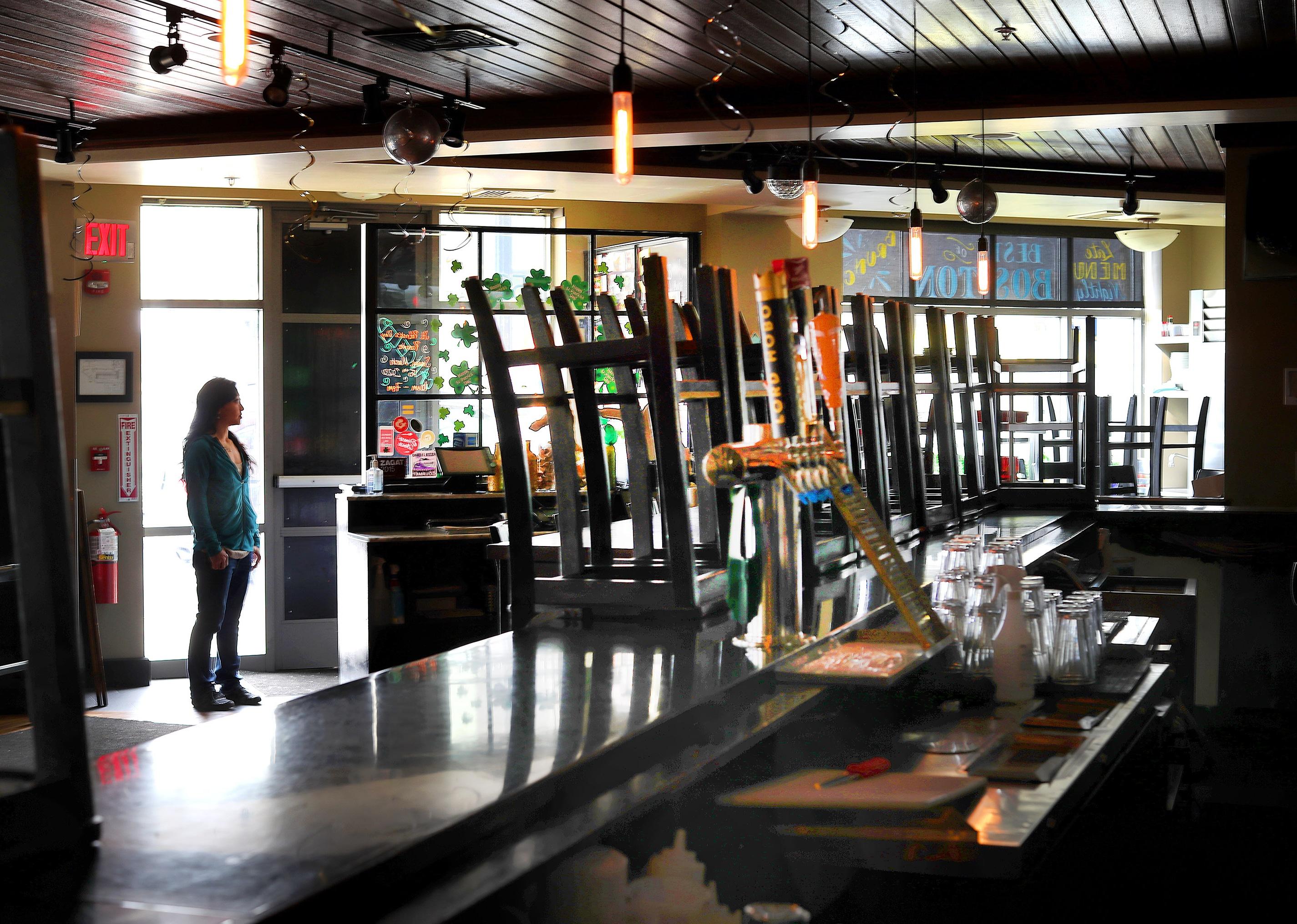 A female business owner standing in a doorway at a closed bar.