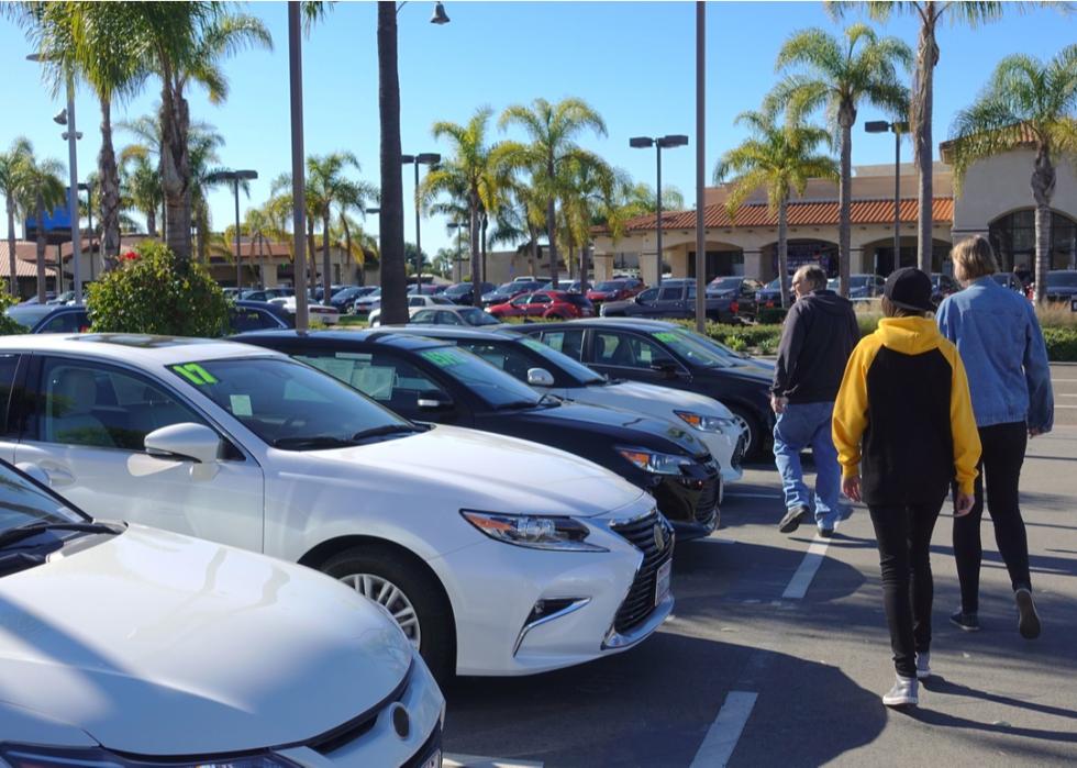 A man shops for used cars with his daughters.