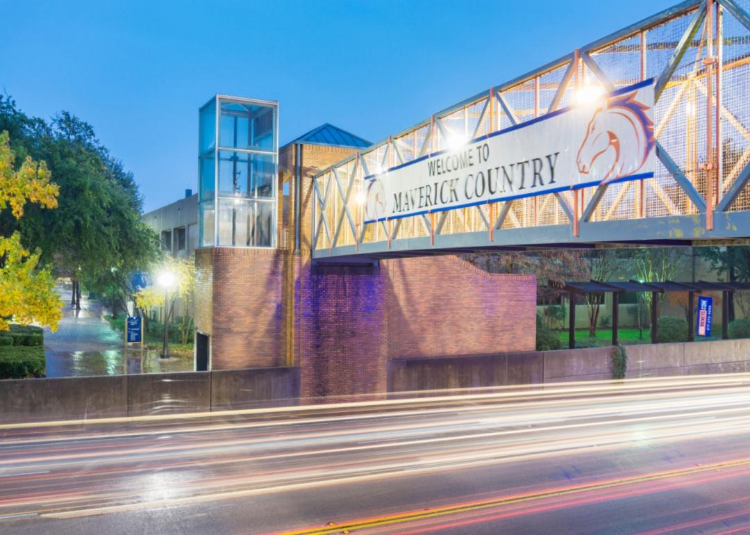 A lit overpass at night with the University of Texas Arlington Mavericks logo.