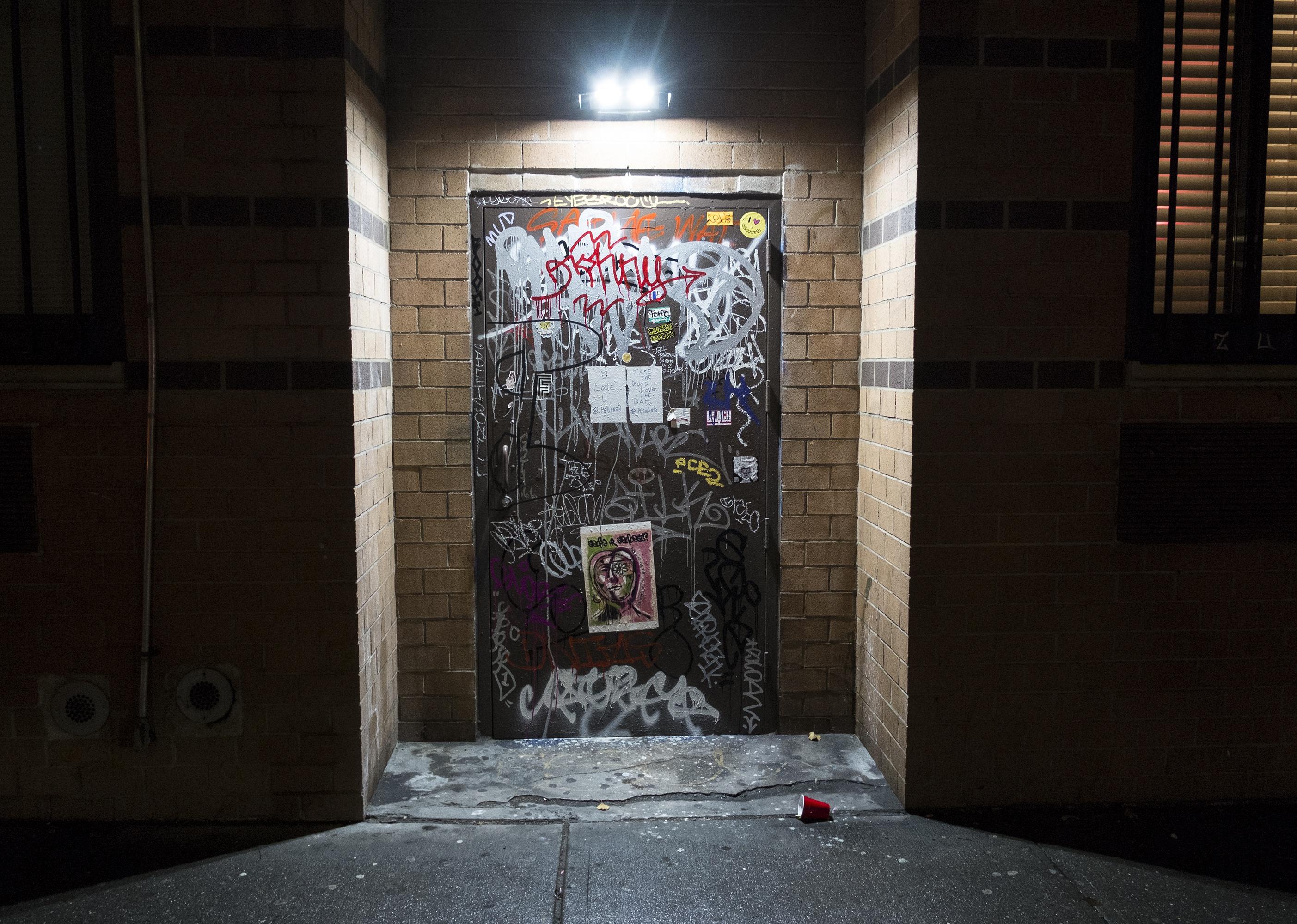 A doorway to a brick building covered in graffiti.