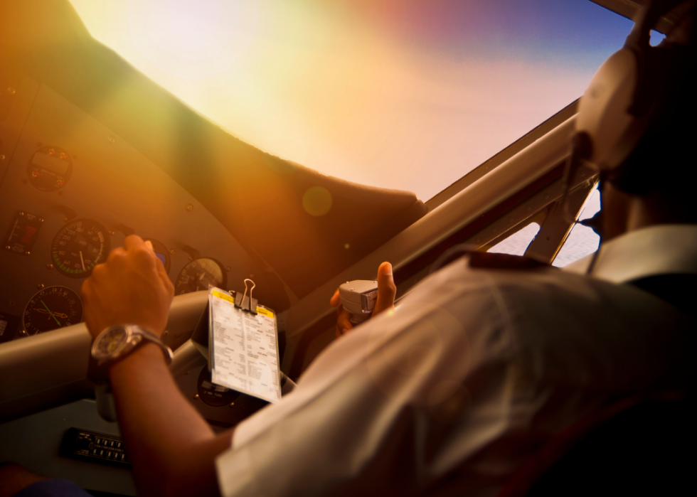 Pilot flying a plane with sunshine coming into the cockpit.