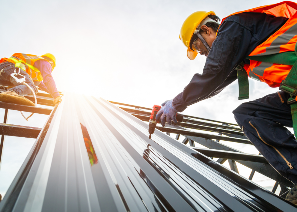Roofers on a steep incline installing materials.