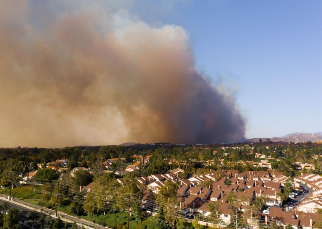 Smoke billowing in the distance from a wildfire heading towards homes.