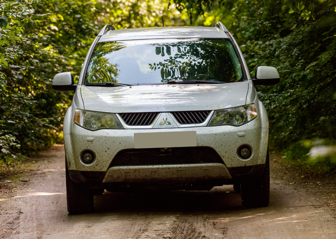 A white Mitsubishi Outlander on a dirt road.