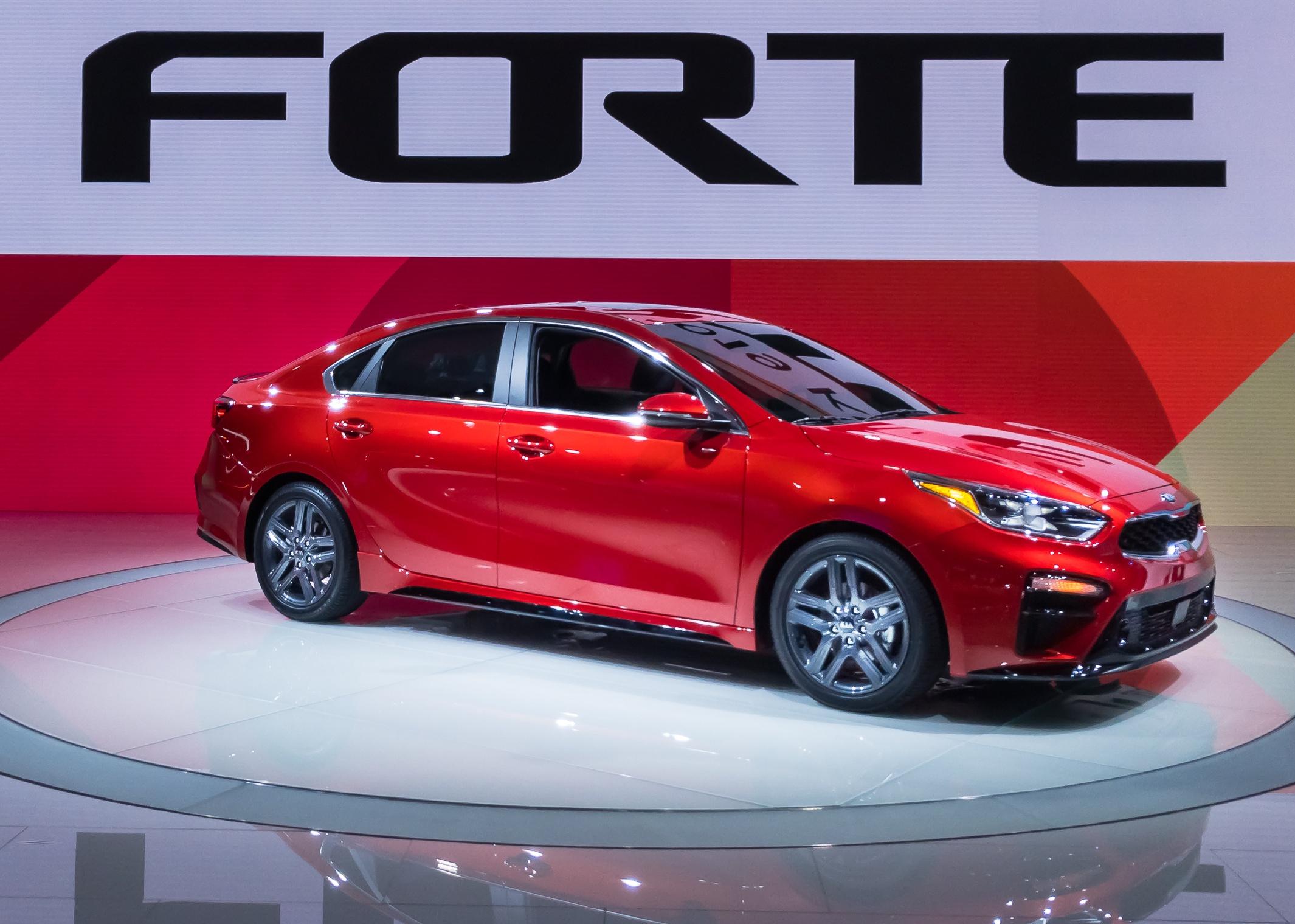 A red Kia Forte on a showroom floor.