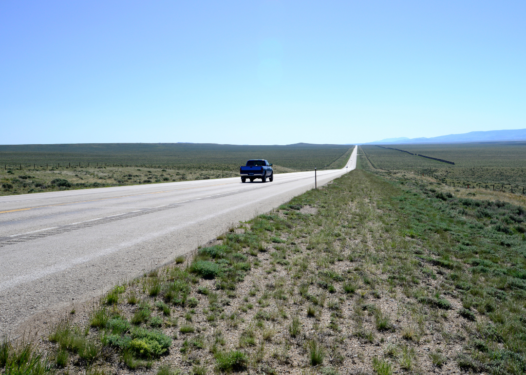 A truck on a country road with mountains in the distance.