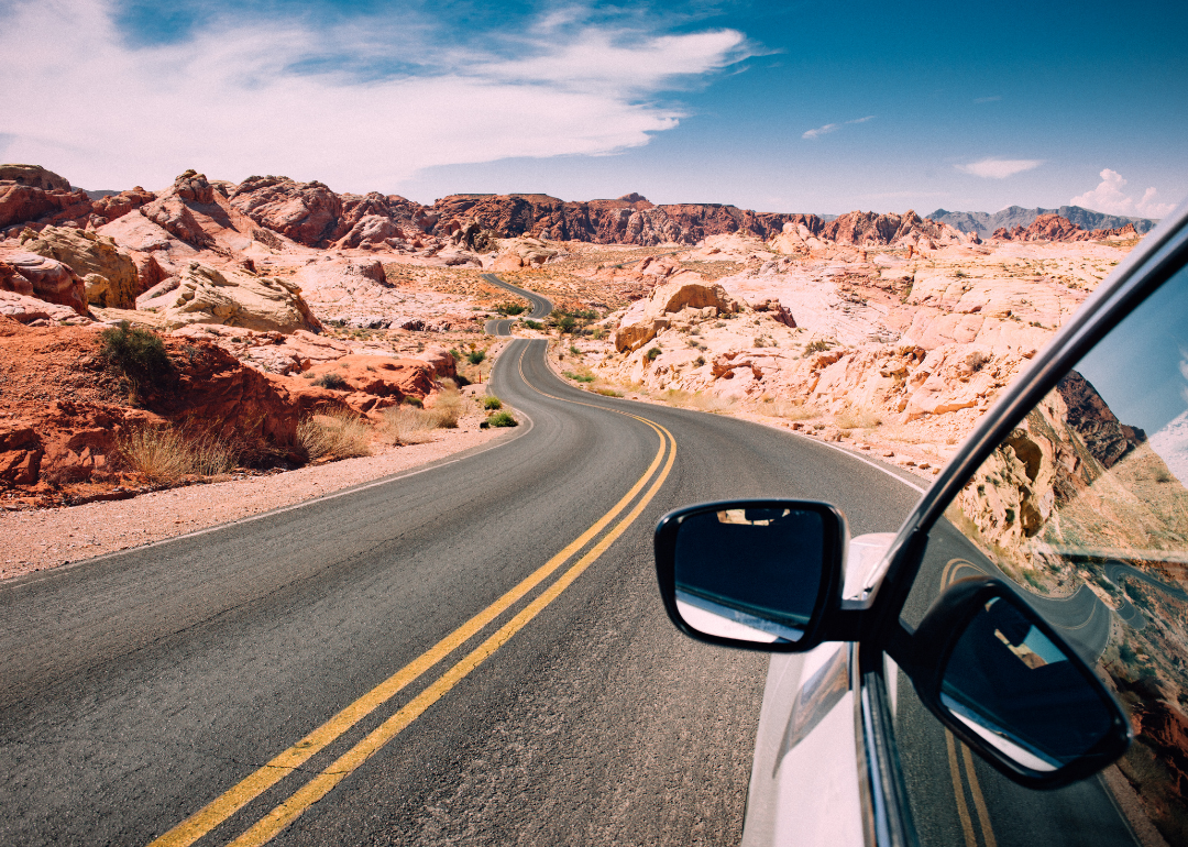 A car on a road winding through rugged mountains.
