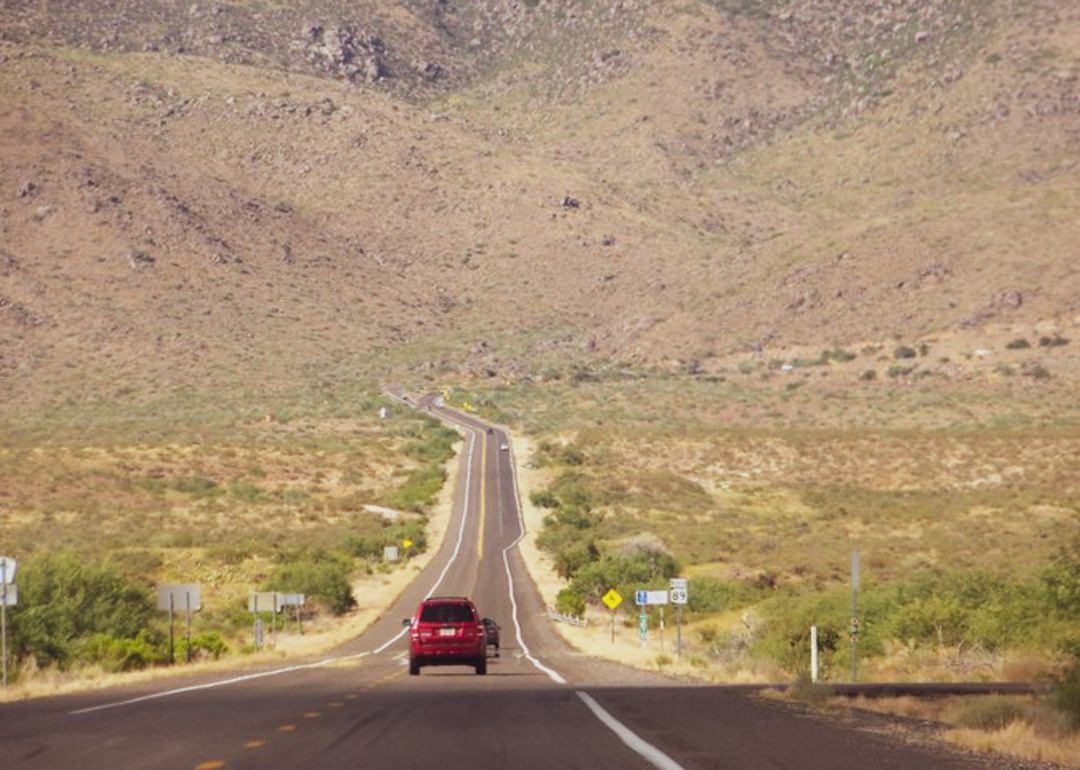 Cars on a highway heading towards a dry mountain landscape.