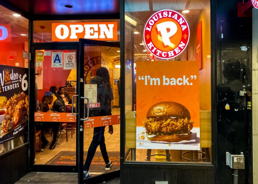 A woman entering a Popeyes restaurant.
