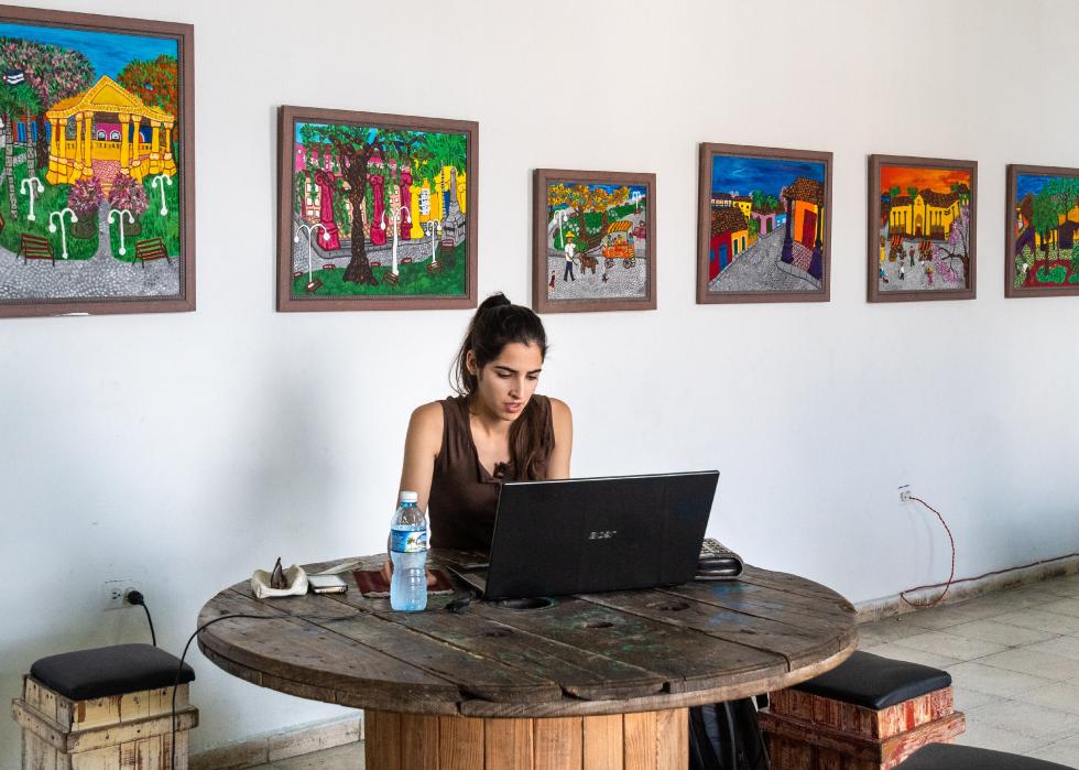 Young woman on a laptop in a Cuban gallery