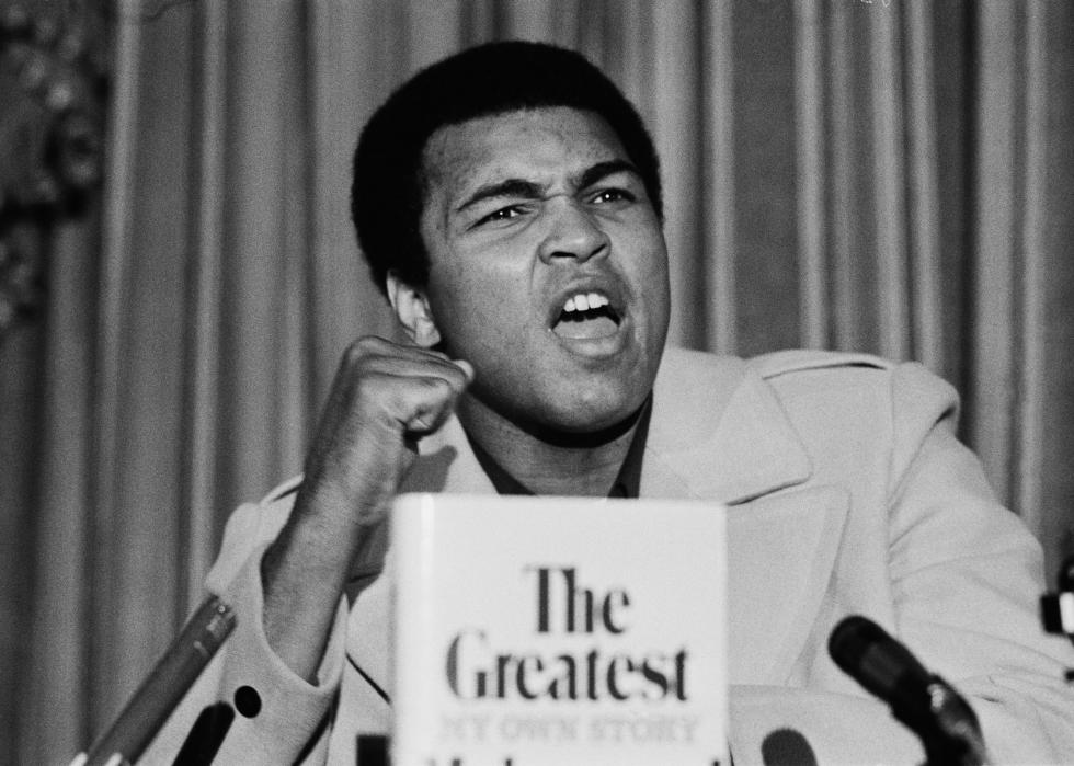 Muhammad Ali poses with book.