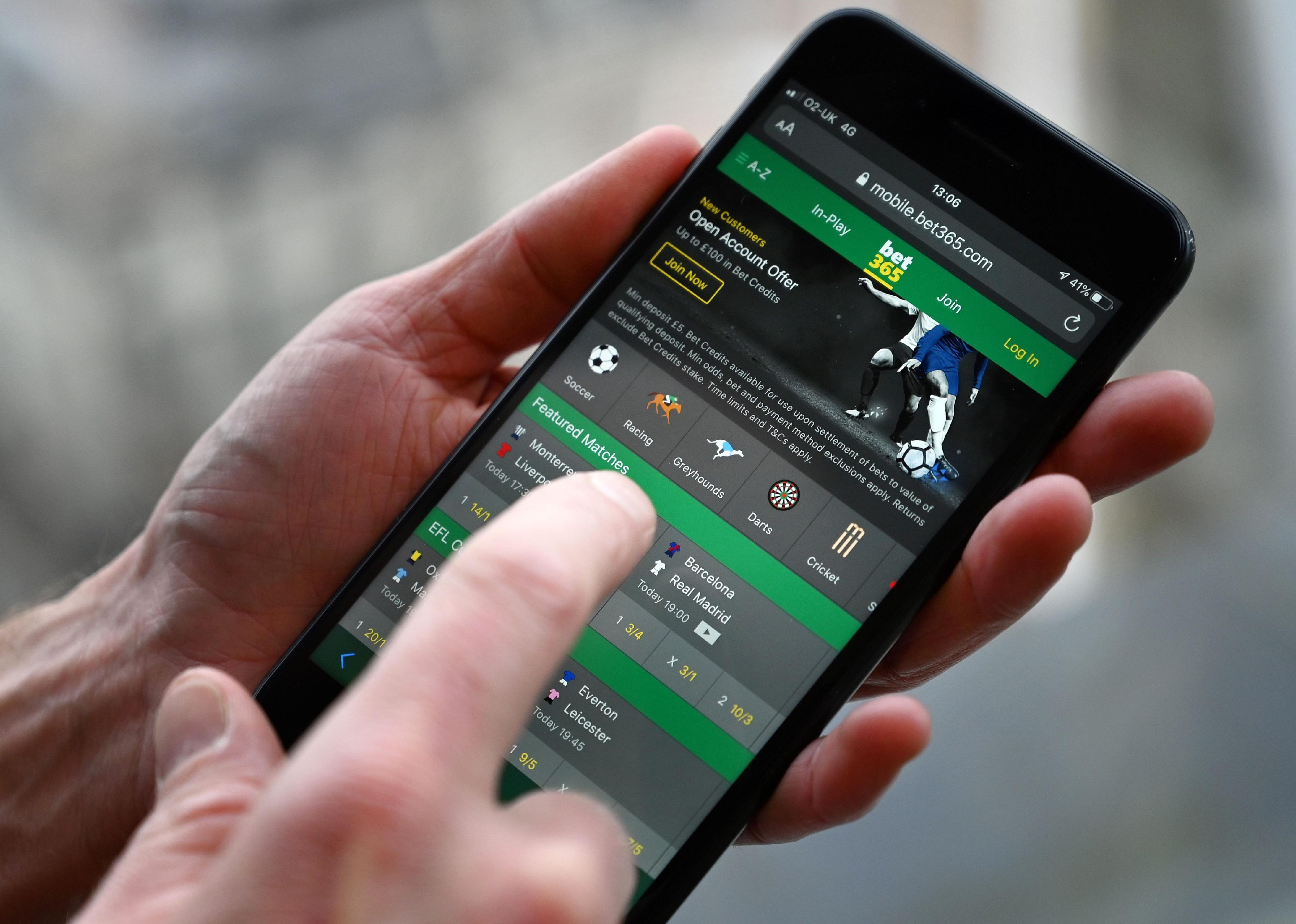 A man poses for a photograph with the online gambling website Bet365 displayed on a smartphone.