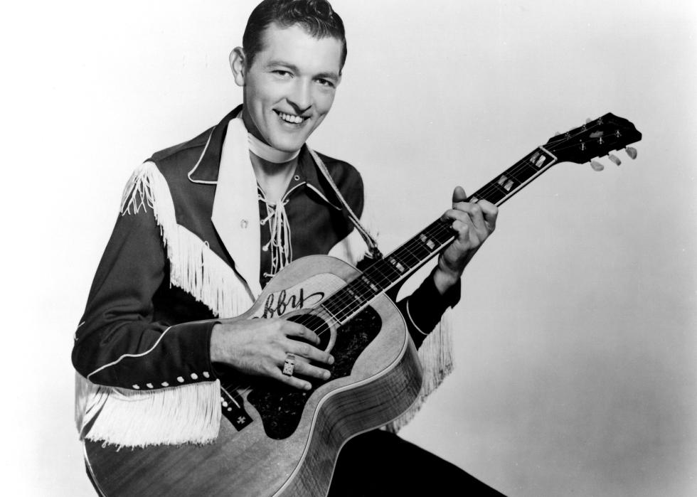 Bobby Helms poses for a portrait hoolding an acoustic guitar.