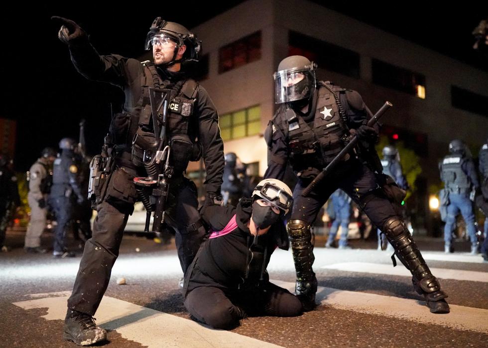 Police officers work to arrest a protester