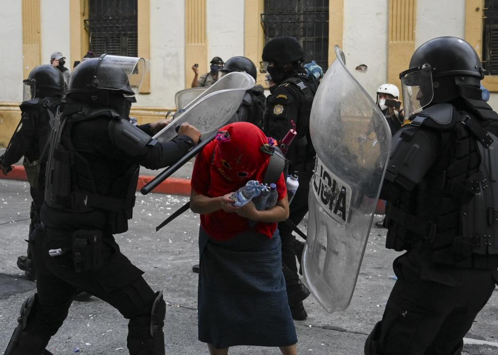 Riot police attack a demonstrator during a protest