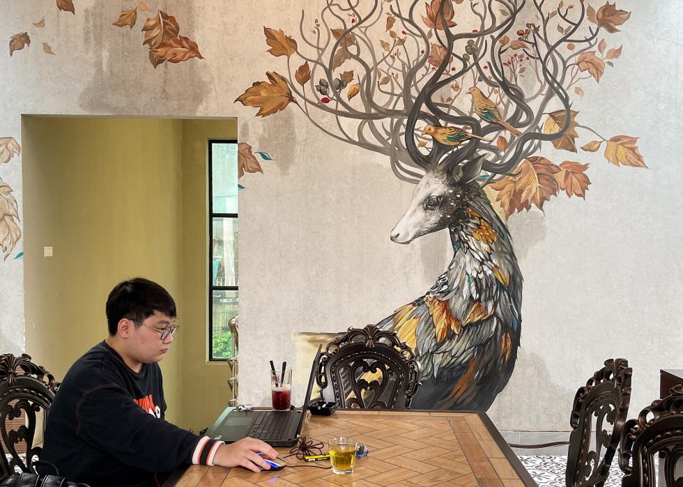 Side view of a man on his laptop at a Vietnamese cafe