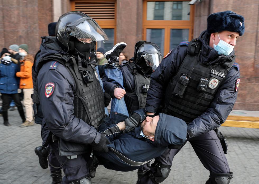 Russian Police officers detain a man during an unsanctioned protest