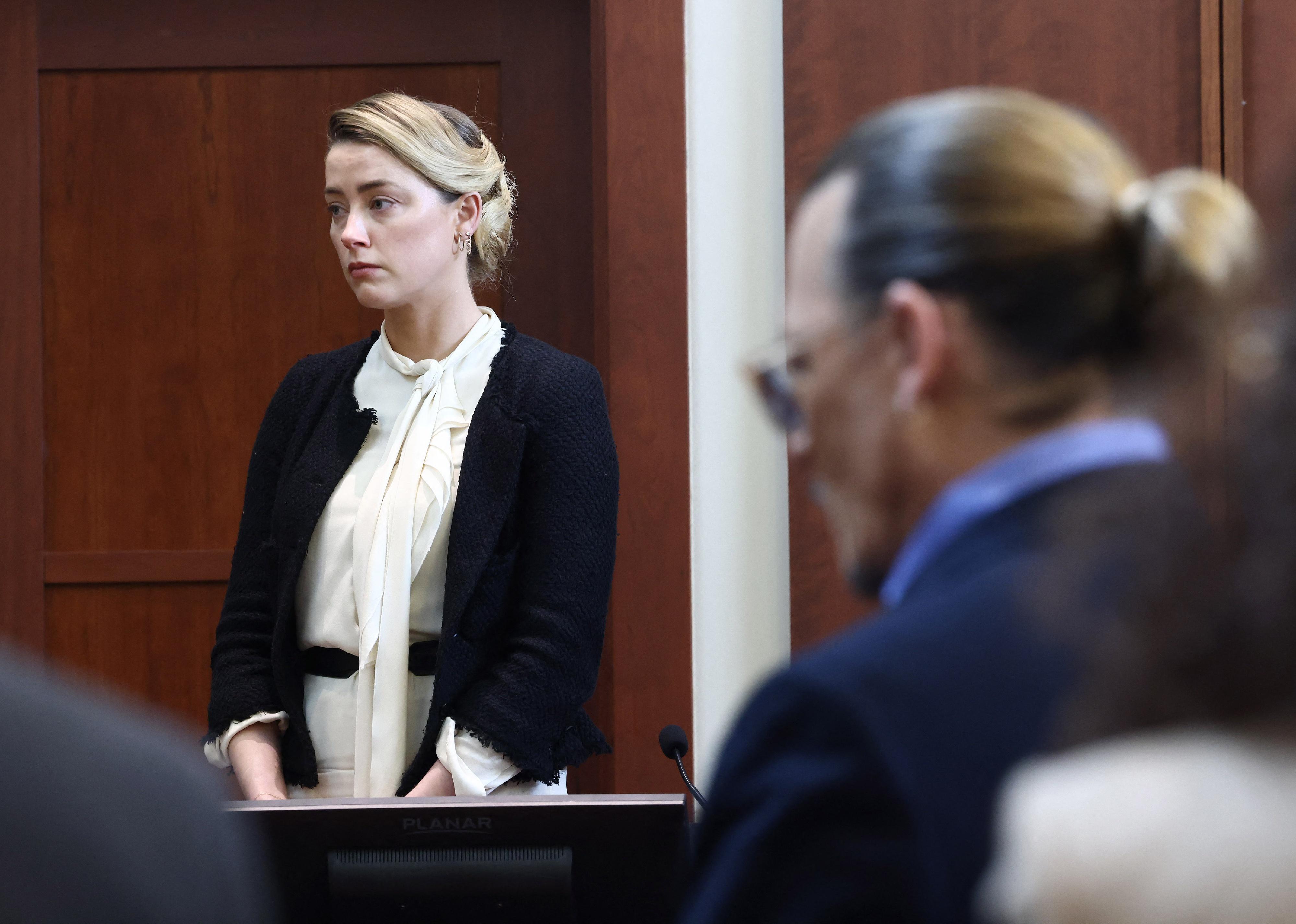 Amber Heard testifies as actor Johnny Depp looks on.