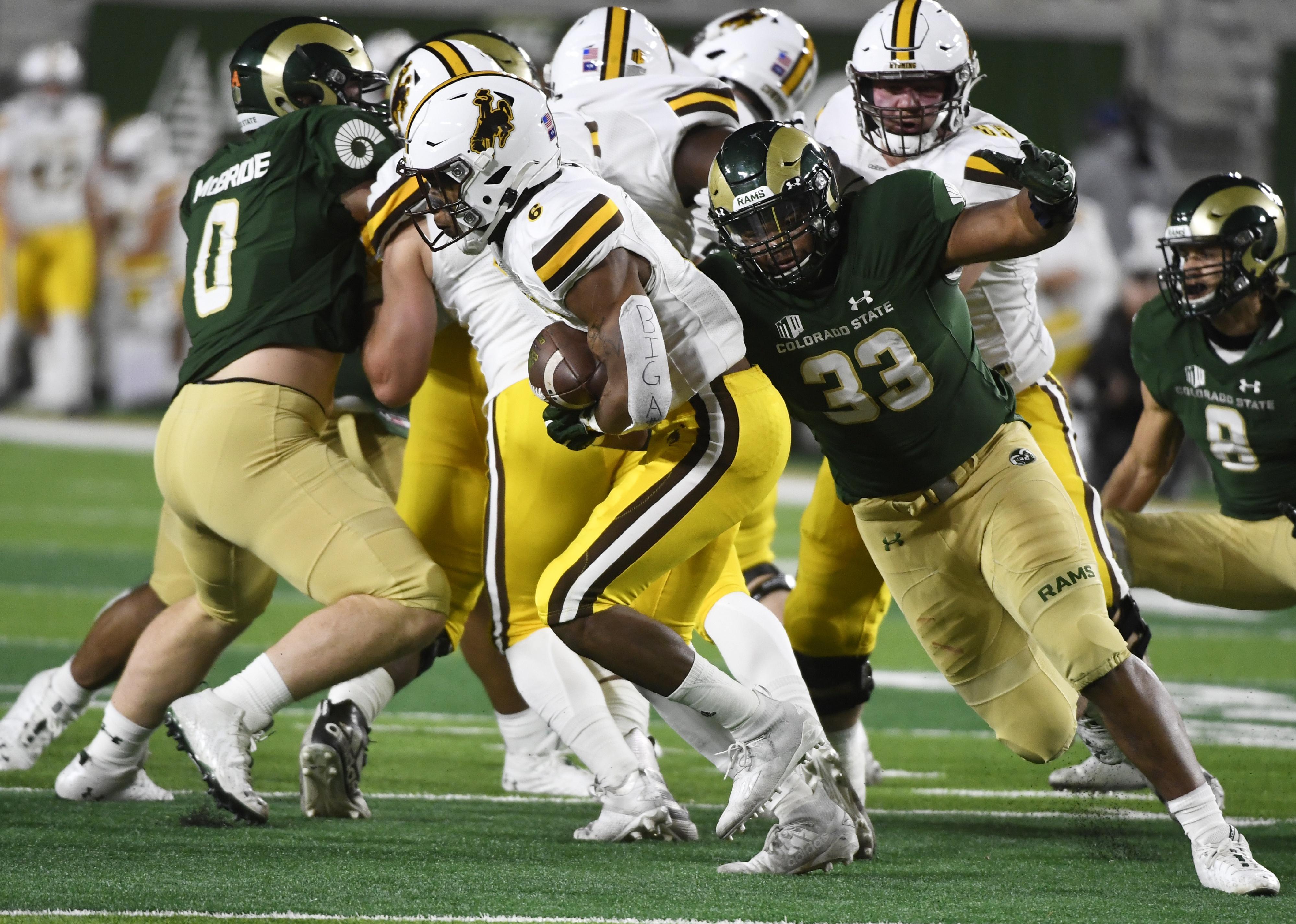 Wyoming Cowboys' Xazavian Valladay and Colorado State Rams defensive lineman Manny Jones in play.