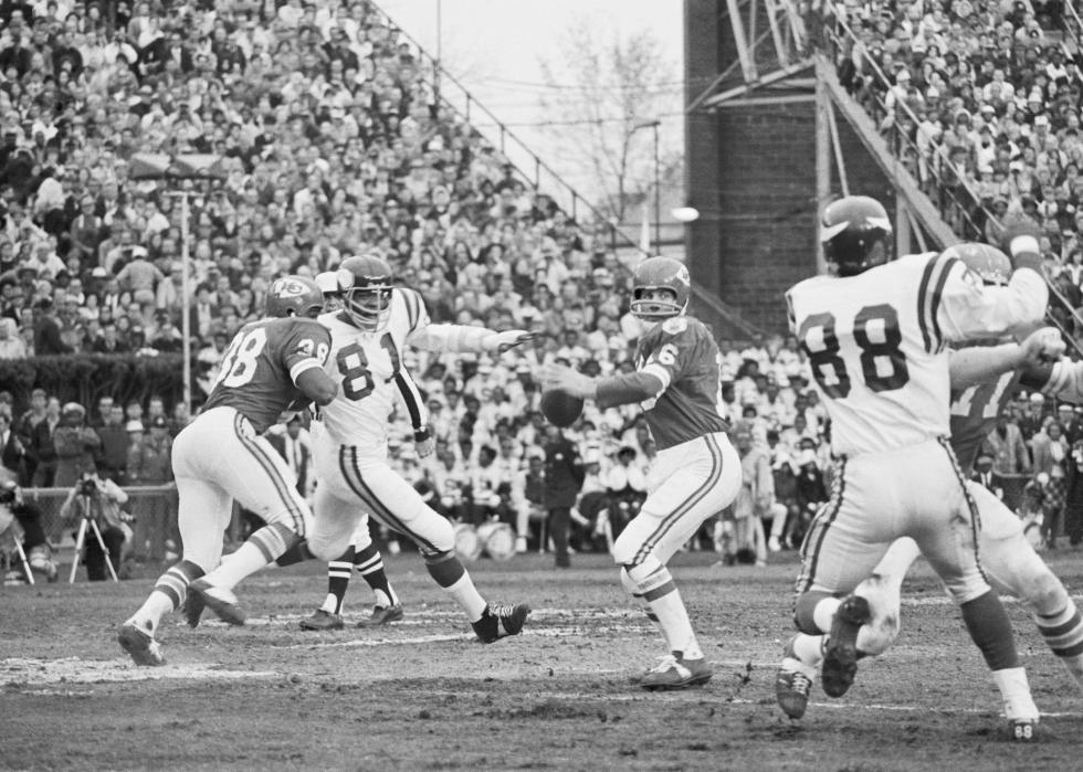 Chiefs Len Dawson getting ready to throw the ball as his teammates hold off Vikings.